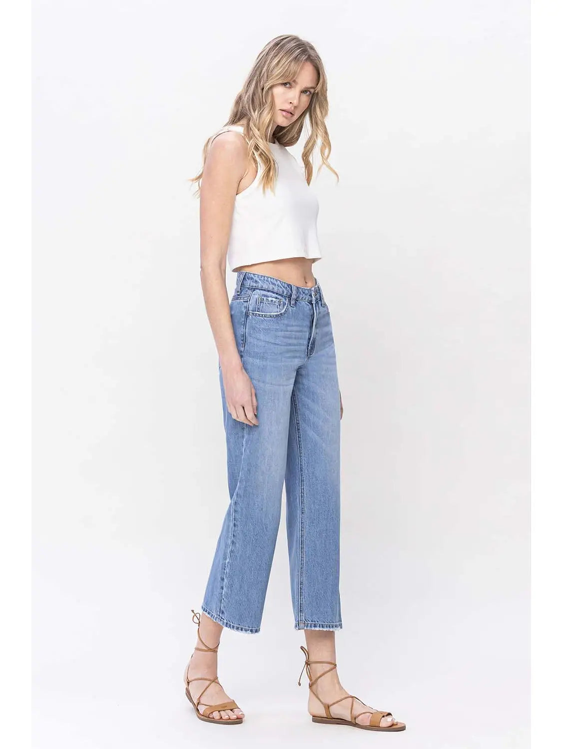 woman wearing HIGH RISE straight DAD denim JEANS with white crop tank and sandals in front of a white background